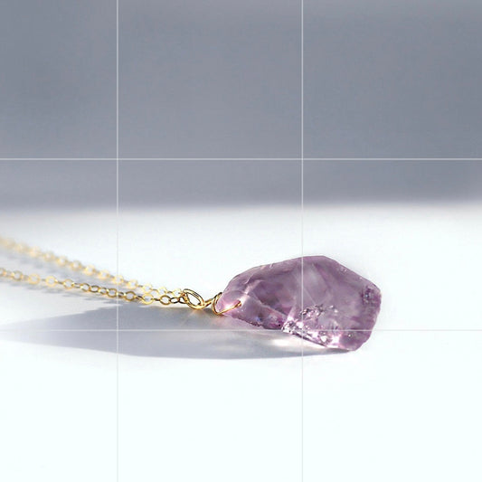 Necklace with a purple crystal pendant on a light gray background