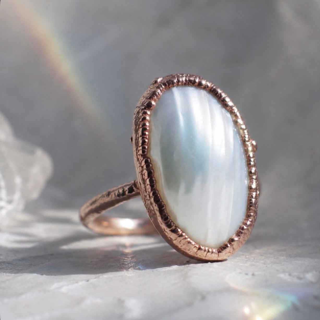 Copper ring with a large white stone on a marble surface