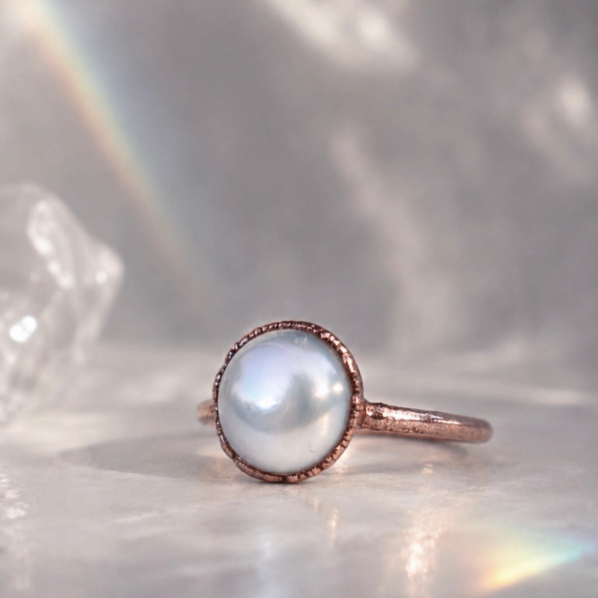 Pearl ring with copper setting on a shell background