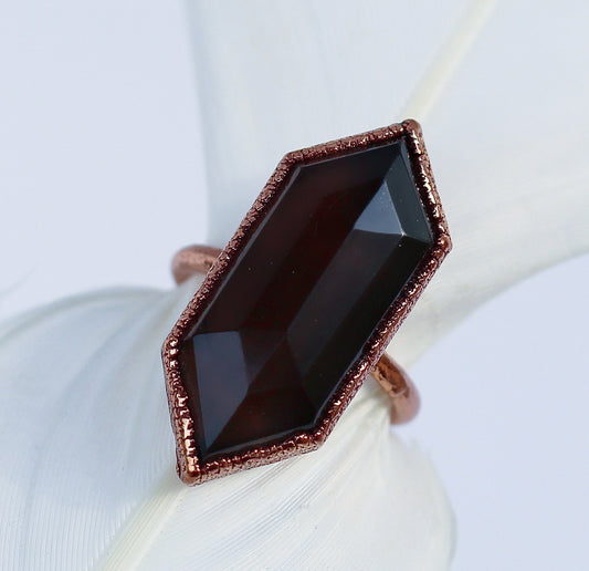 A double terminated smoky quartz crystal set in a copper ring, displayed on a white fabric.